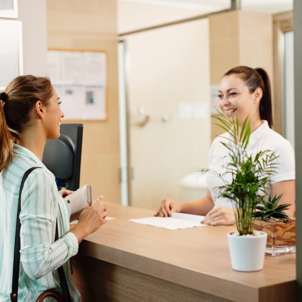 happy-woman-talking-receptionist-while-arriving-spa